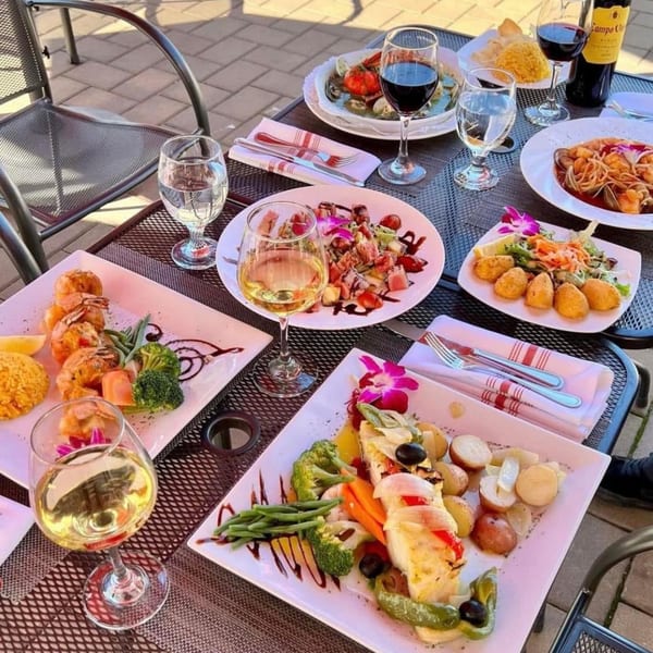An outdoor table at Assado Portuguese Steakhouse laden with various Portuguese dishes and wine.