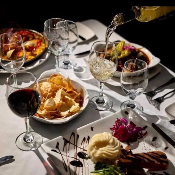 White wine being poured into a glass at a table set with Portuguese dishes and red wine.